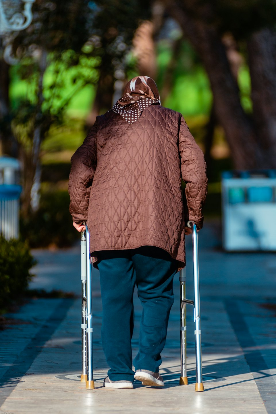 Person with walker strolls on park path.