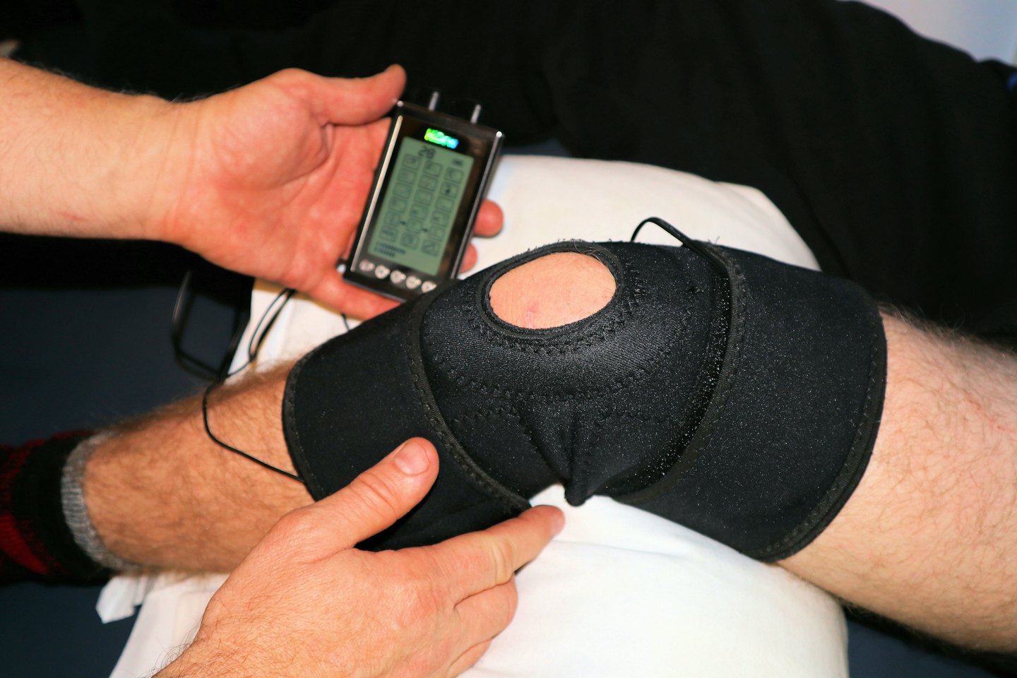 Medical professional adjusts knee brace with electronic device.